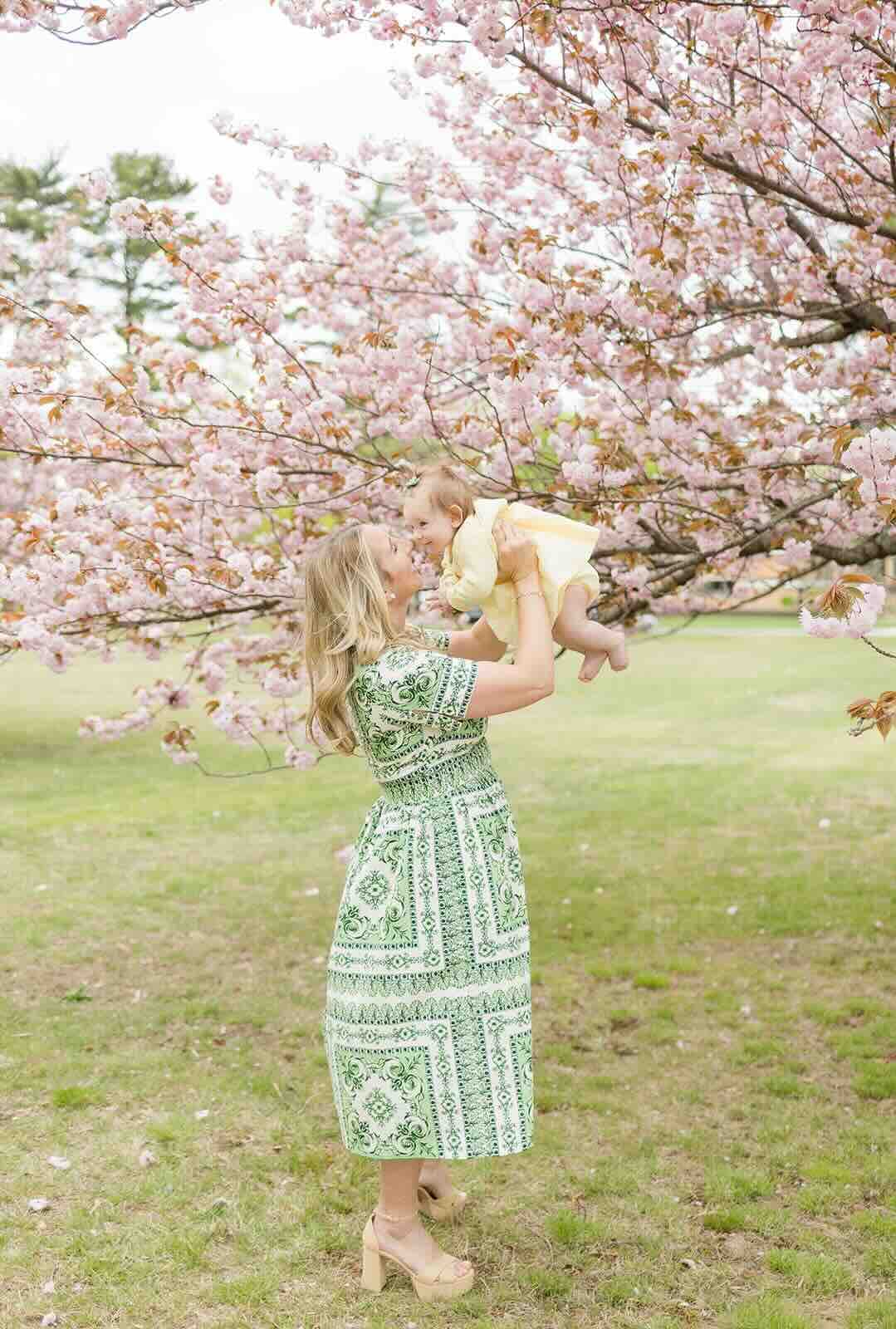 Nicole holding her daughter Avery beneath cherry blossoms